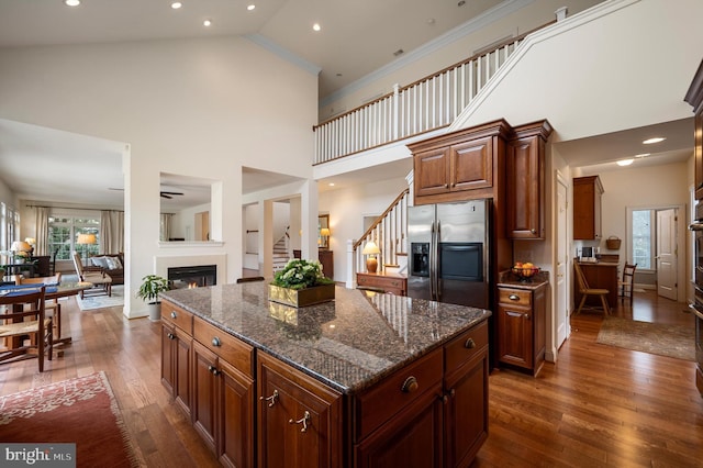 kitchen featuring dark wood-style flooring, a glass covered fireplace, stainless steel fridge with ice dispenser, and ornamental molding