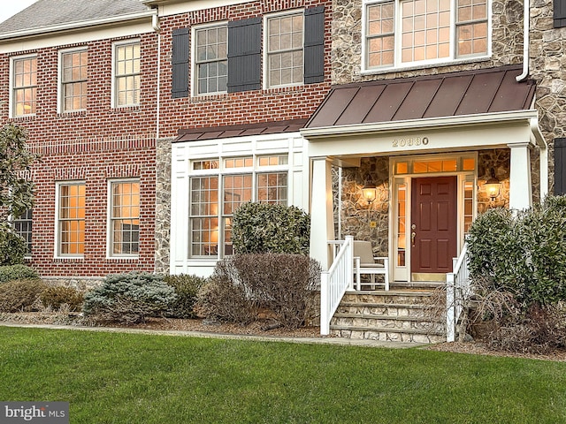 property entrance featuring a standing seam roof, a shingled roof, stone siding, brick siding, and metal roof