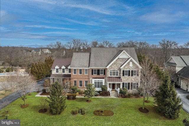 view of front of home with metal roof, stone siding, a front lawn, and a standing seam roof