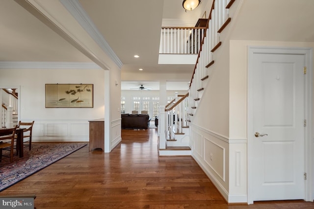 foyer entrance featuring stairway, a wainscoted wall, dark wood finished floors, recessed lighting, and ornamental molding