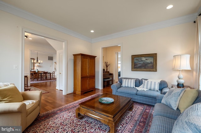 living room featuring recessed lighting, crown molding, an inviting chandelier, and wood finished floors