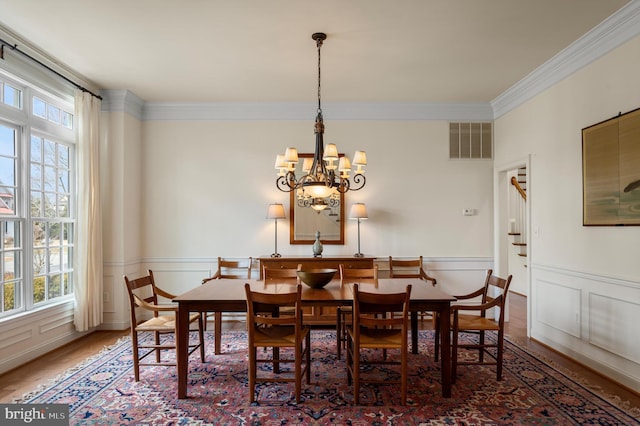 dining room with plenty of natural light, wainscoting, visible vents, and ornamental molding