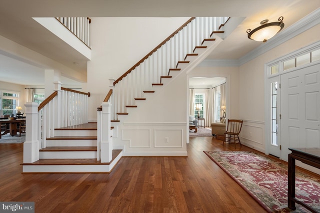 entrance foyer with plenty of natural light, wood finished floors, stairs, and crown molding