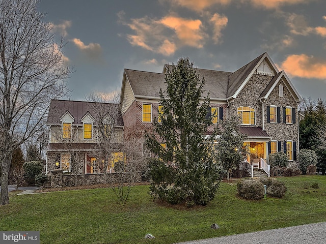 traditional-style home featuring brick siding, stone siding, and a front yard