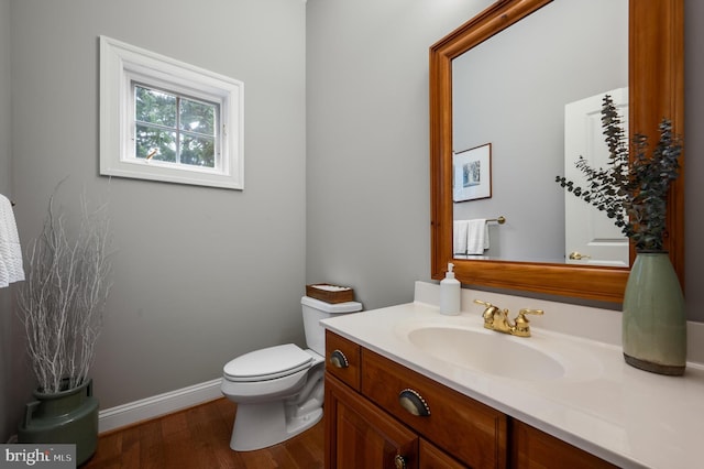 bathroom featuring baseboards, toilet, wood finished floors, and vanity