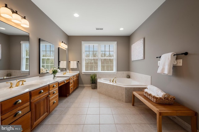 bathroom with tile patterned floors, a garden tub, a wealth of natural light, and a sink