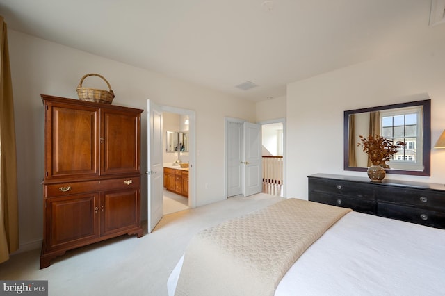 bedroom with connected bathroom and light carpet