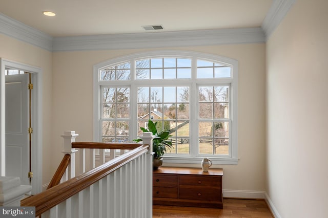 interior space featuring visible vents, baseboards, wood finished floors, and ornamental molding