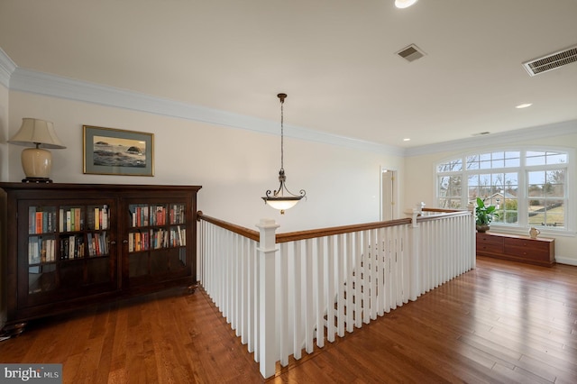 corridor featuring visible vents, wood finished floors, and ornamental molding