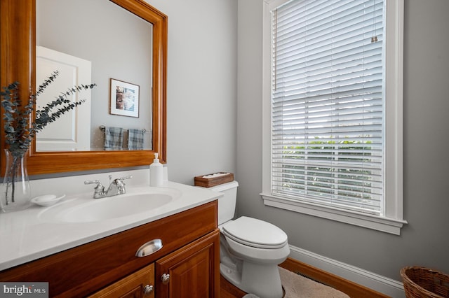 half bath with toilet, vanity, and baseboards