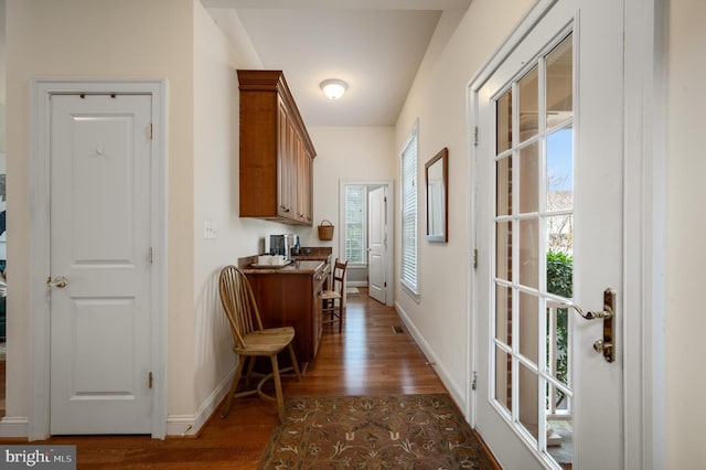 hall with visible vents, baseboards, and dark wood finished floors