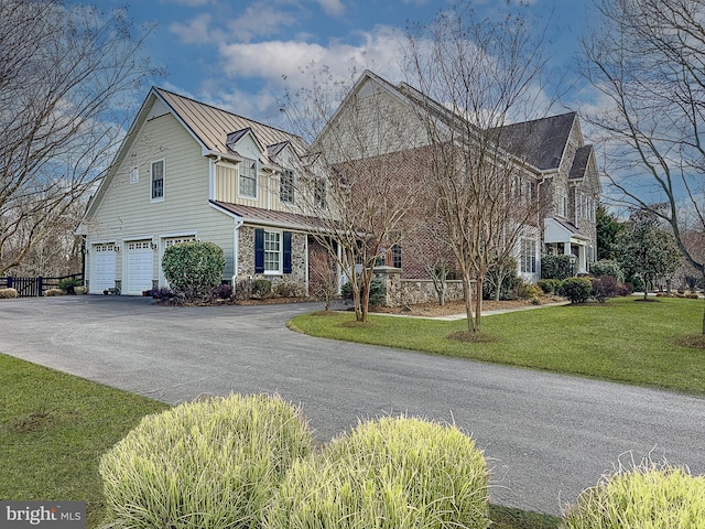 view of front of home with a standing seam roof, an attached garage, a front lawn, aphalt driveway, and metal roof