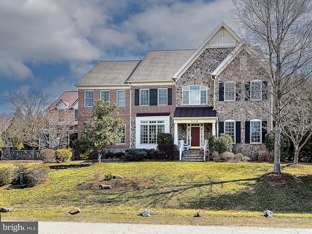 view of front of house featuring stone siding, brick siding, and a front yard