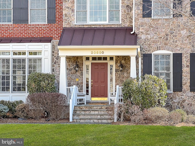 property entrance with stone siding, metal roof, and a standing seam roof