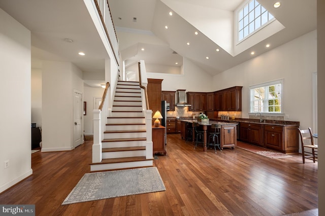 kitchen with a kitchen breakfast bar, dark wood-style flooring, a center island, and wall chimney range hood