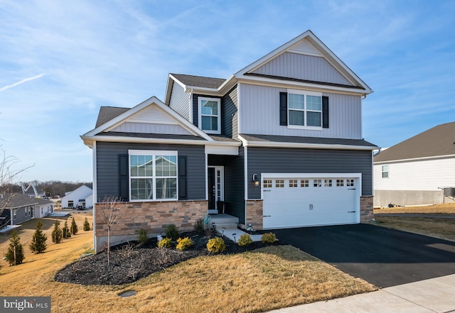 view of front of house featuring an attached garage, stone siding, and driveway