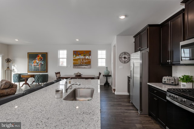 kitchen featuring a sink, recessed lighting, light stone countertops, and stainless steel appliances