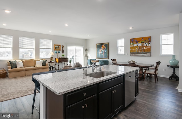 kitchen with a center island with sink, dark wood finished floors, a sink, dishwasher, and open floor plan