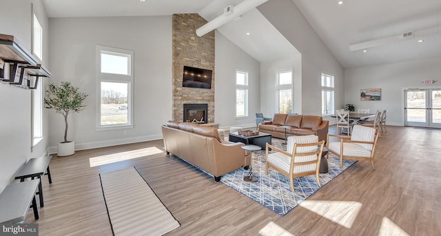 living room with light wood-style flooring, a fireplace, visible vents, and high vaulted ceiling