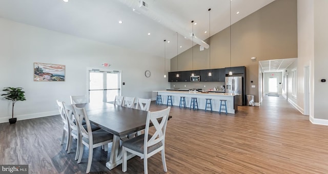 dining space featuring visible vents, baseboards, high vaulted ceiling, and light wood-style flooring