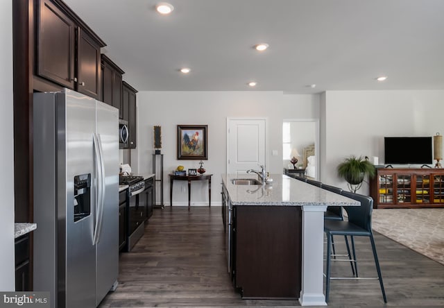 kitchen featuring a center island with sink, a sink, dark wood-style floors, open floor plan, and stainless steel appliances