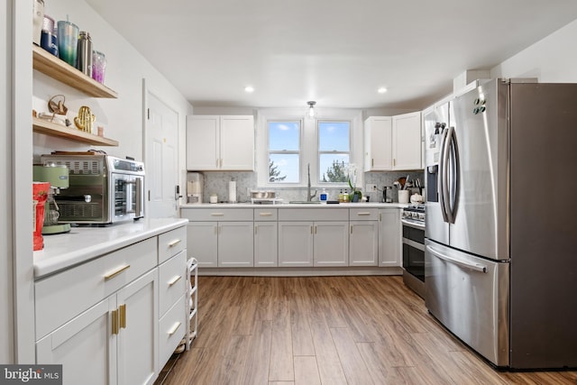 kitchen with a sink, tasteful backsplash, wood finished floors, stainless steel appliances, and light countertops