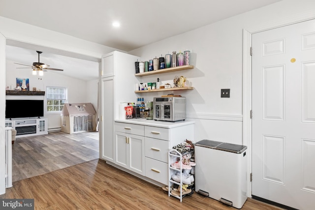 kitchen featuring a ceiling fan, lofted ceiling, light countertops, wainscoting, and light wood-type flooring