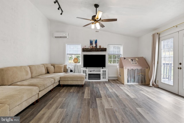 living area with a wall mounted air conditioner, plenty of natural light, wood finished floors, and vaulted ceiling