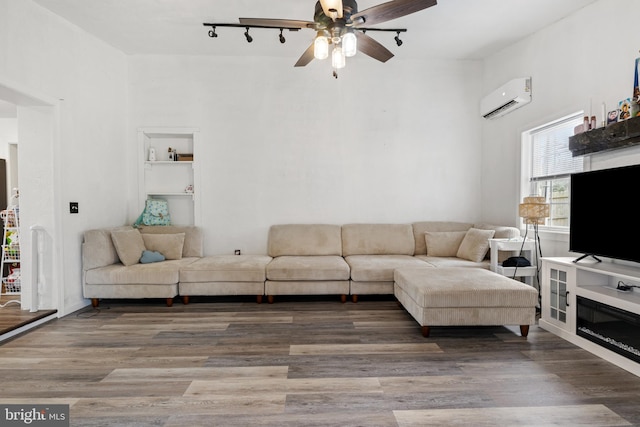 living room with wood finished floors, a ceiling fan, and a wall mounted AC