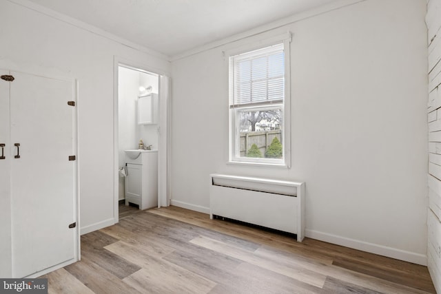 unfurnished bedroom featuring radiator heating unit, baseboards, and wood finished floors