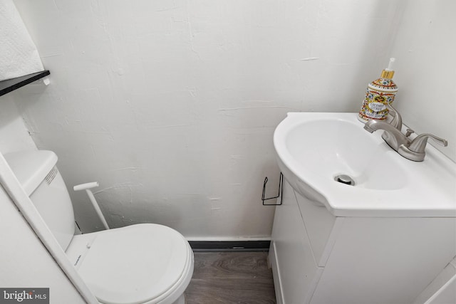 half bathroom with vanity, toilet, and wood finished floors