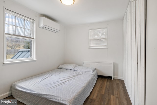 bedroom with a wall mounted air conditioner, baseboards, radiator, and dark wood-style flooring