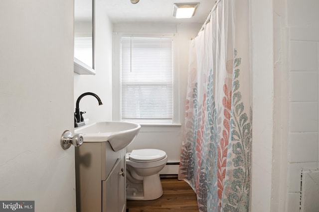 bathroom with toilet, a shower with curtain, wood finished floors, vanity, and a baseboard radiator