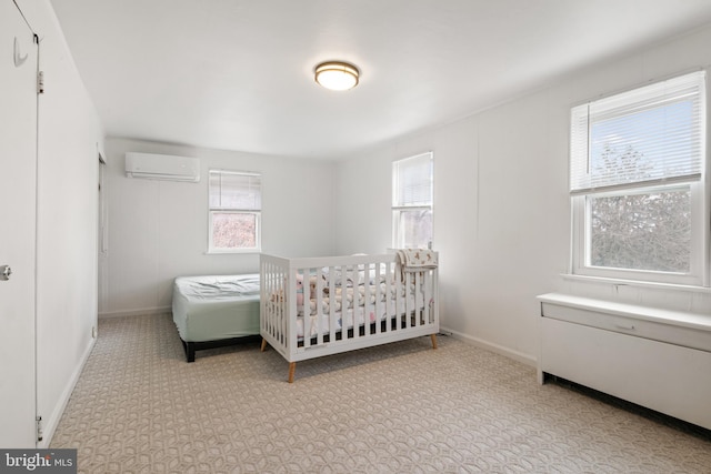 bedroom with a wall unit AC, multiple windows, and baseboards