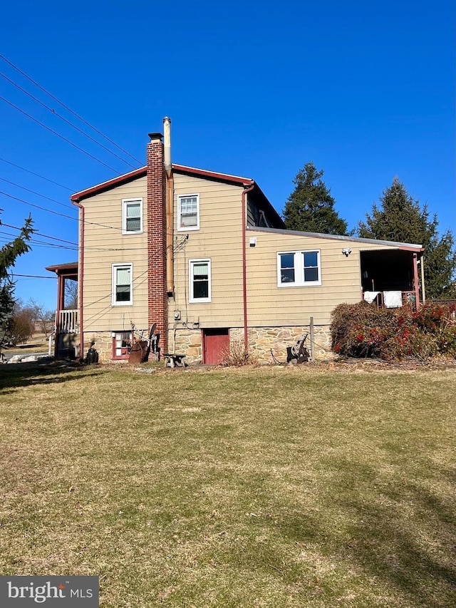 rear view of house with a lawn and a chimney