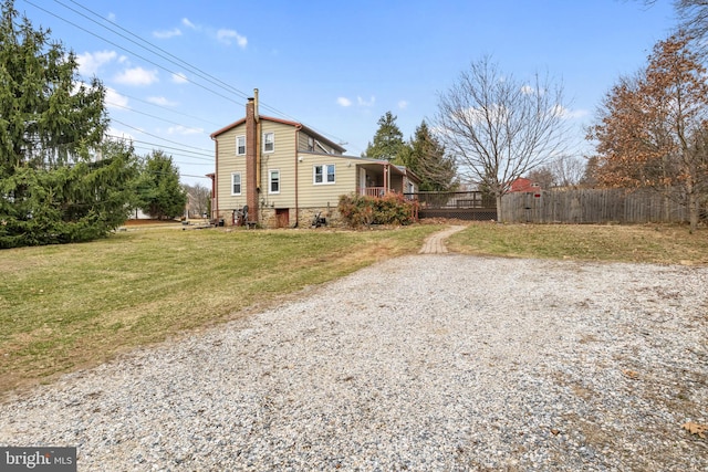 view of front of property featuring a porch, a chimney, a front yard, and fence