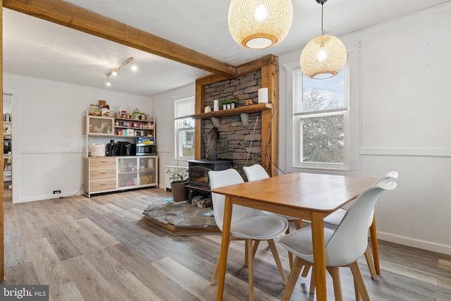 dining space with a wood stove, plenty of natural light, and light wood-style floors