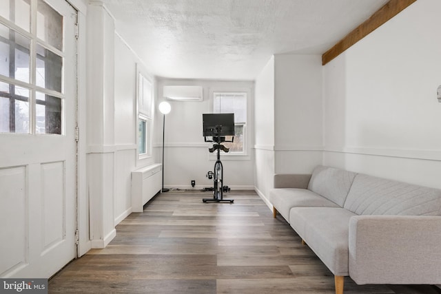 living area featuring baseboards, a textured ceiling, wood finished floors, and a wall mounted AC