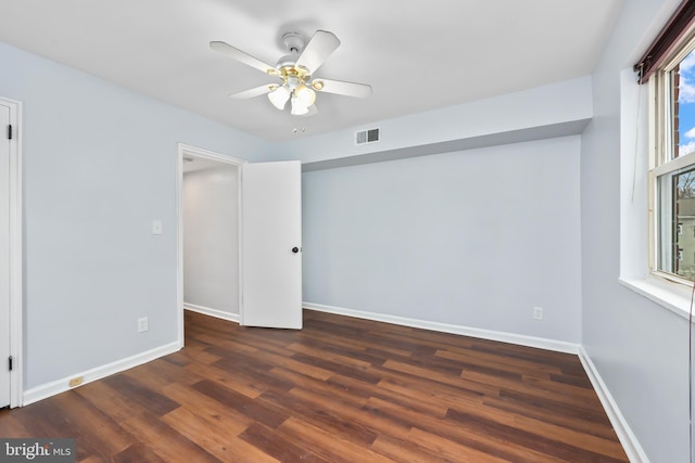 empty room with ceiling fan, visible vents, baseboards, and wood finished floors