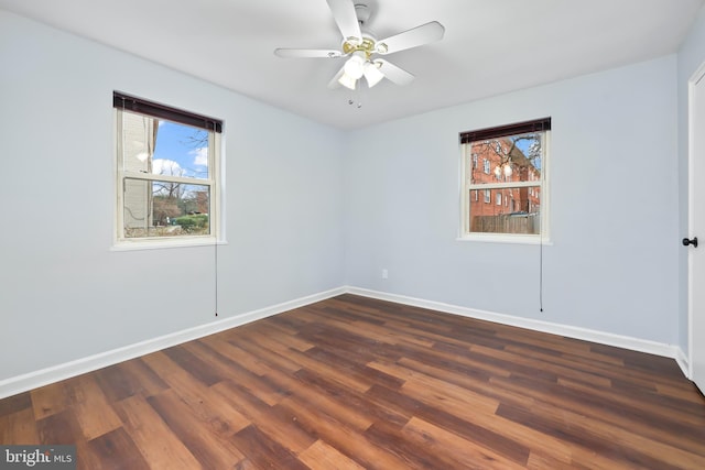 unfurnished room featuring baseboards, dark wood-style floors, and a ceiling fan