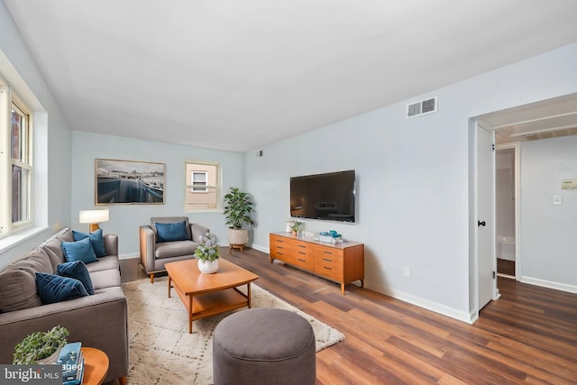 living area with wood finished floors, visible vents, and baseboards