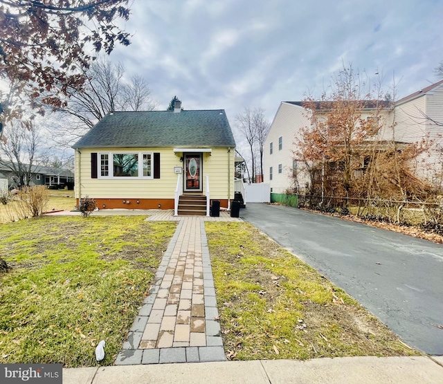 bungalow with entry steps, aphalt driveway, fence, a shingled roof, and crawl space