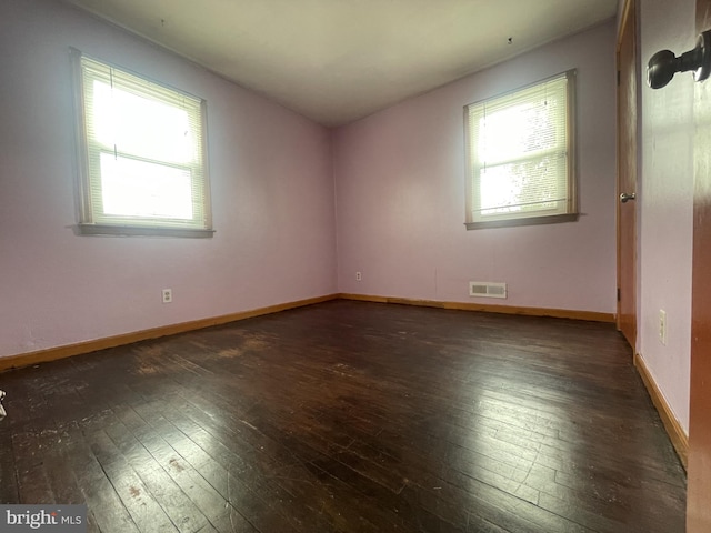 empty room featuring baseboards, visible vents, and wood-type flooring