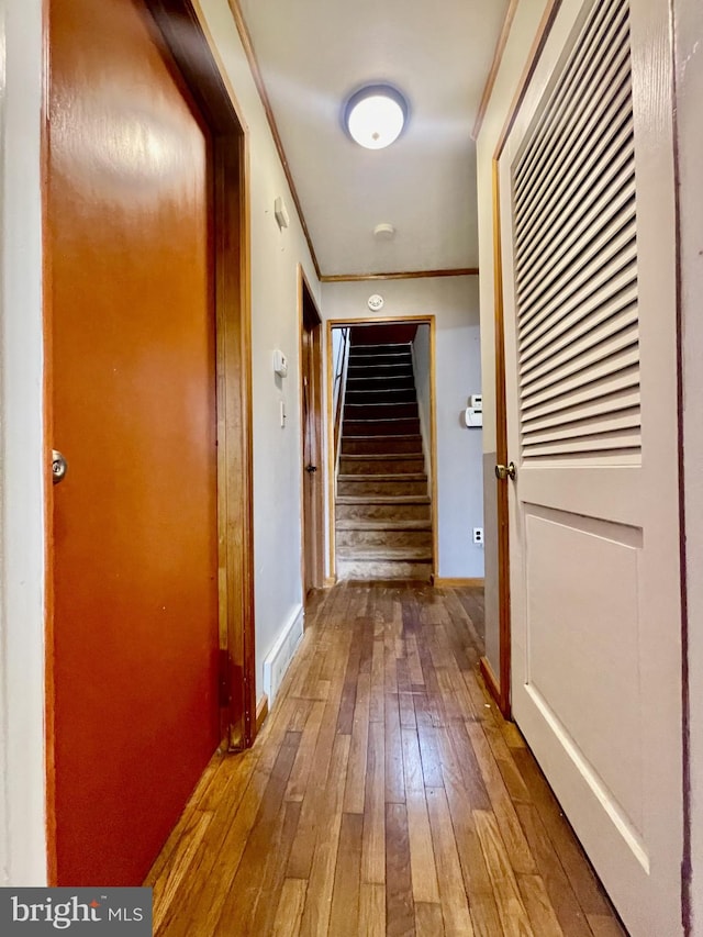 hallway with hardwood / wood-style floors, stairway, baseboards, and ornamental molding