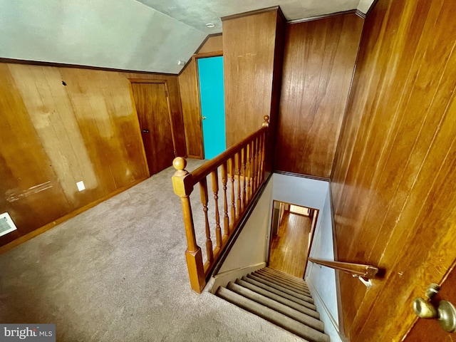 staircase with lofted ceiling, wooden walls, and carpet flooring