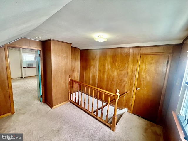 interior space featuring wood walls, carpet, and vaulted ceiling