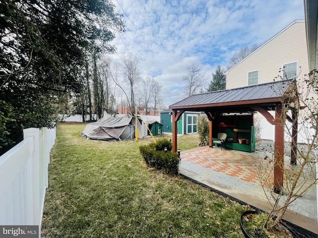 view of yard featuring an outdoor structure, a patio, and fence