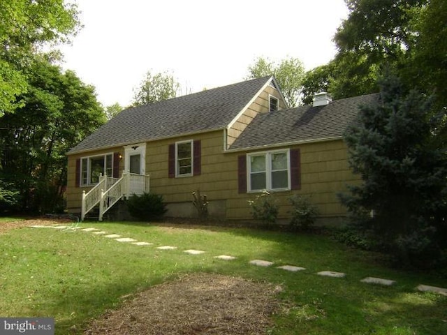 view of front of home featuring a chimney, a front yard, and roof with shingles