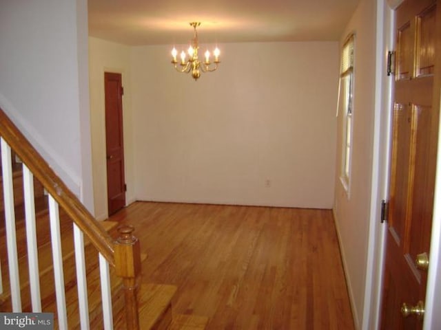 interior space featuring stairway, light wood-type flooring, and an inviting chandelier