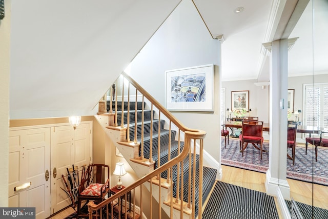 stairs featuring wood finished floors, baseboards, and ornamental molding